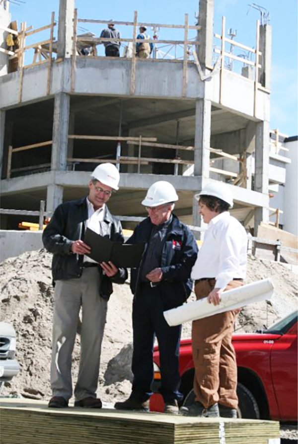 Three construction workers in hardhats collaborating on the job