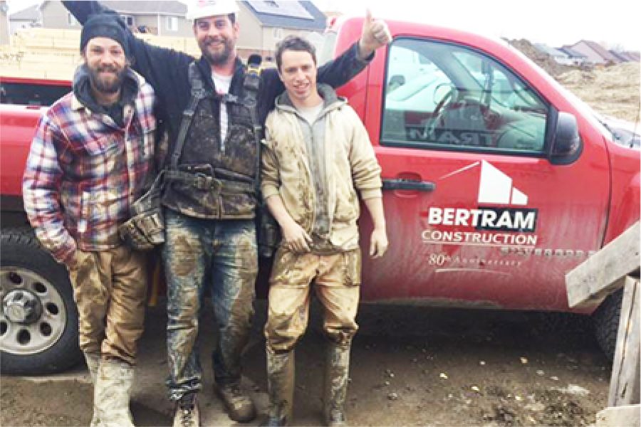 Group of three construction workers posing for photo in front of Bertram Construction truck