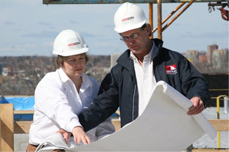 Two construction workers in hardhats looking at a drawing on site